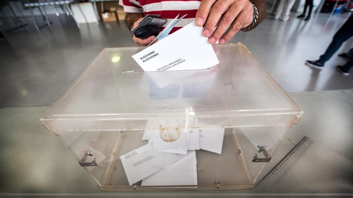 Una persona depositando su voto en la urna.