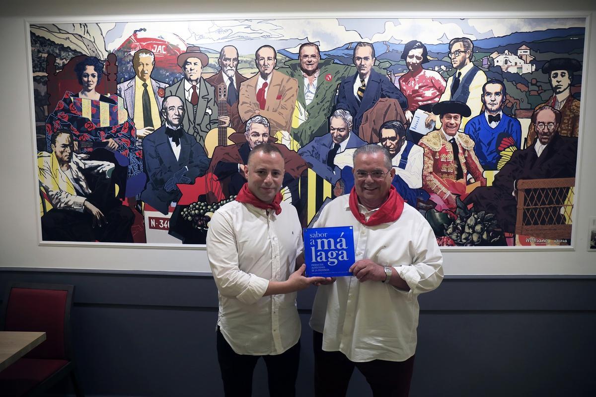 Padre e hijo, con el distintivo de Sabor a Málaga delante de un mural de Chicano.