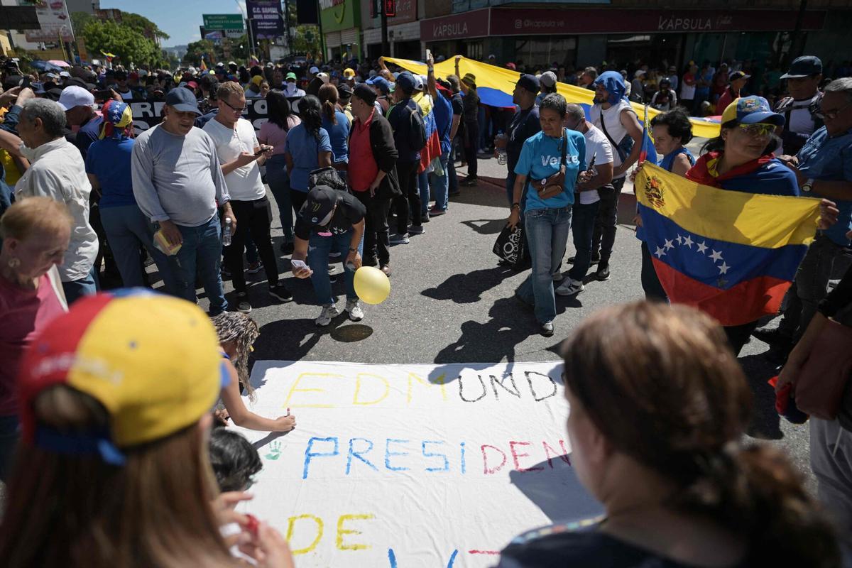 A demonstrator writes on a banner Edmundo President during a protest called by the opposition on the eve of the presidential inauguration in Caracas on January 9, 2025. Venezuela is on tenterhooks facing demonstrations called by both the opposition and government supporters a day before President Nicolas Maduro is due to be sworn in for a third consecutive term and despite multiple countries recognizing opposition rival Edmundo Gonzalez Urrutia as the legitimate president-elect following elections past July. (Photo by JUAN BARRETO / AFP)