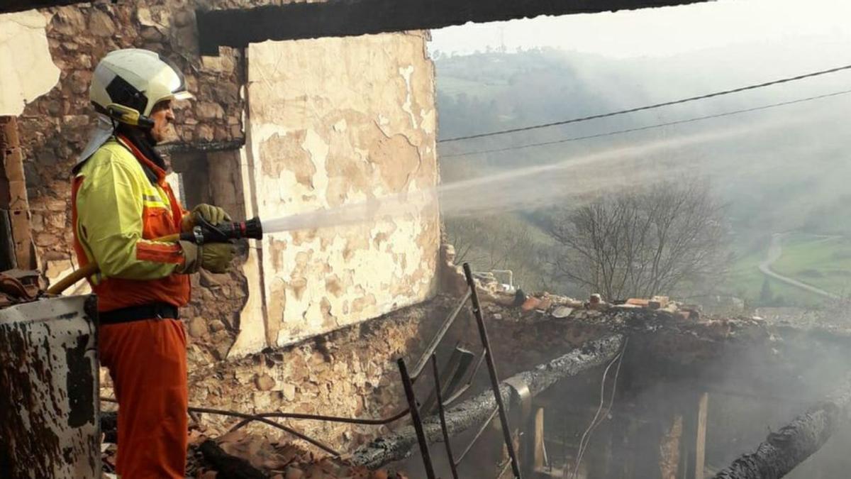 Un bombero apaga el fuego en una casa de Sobrevega (Grado).