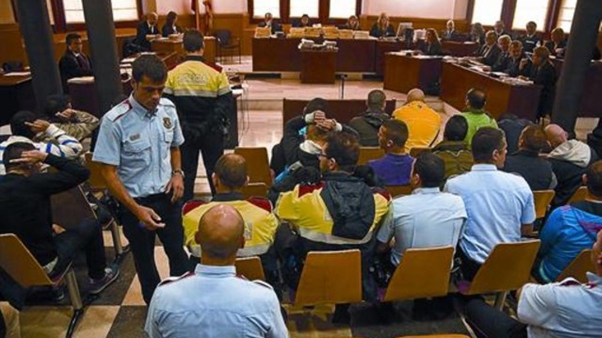 Agentes de los Mossos custodian a los procesados, al principio de la sesión de ayer.