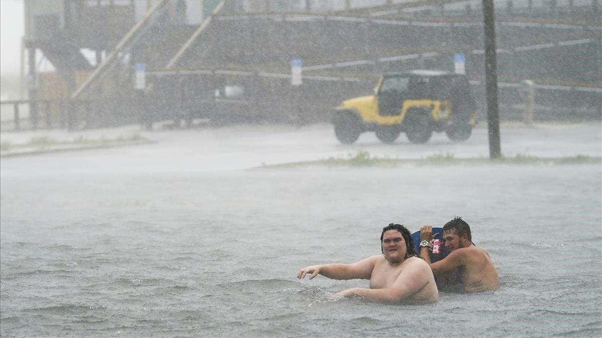 Unas personas en un parking inundado en Navarre Beach. 