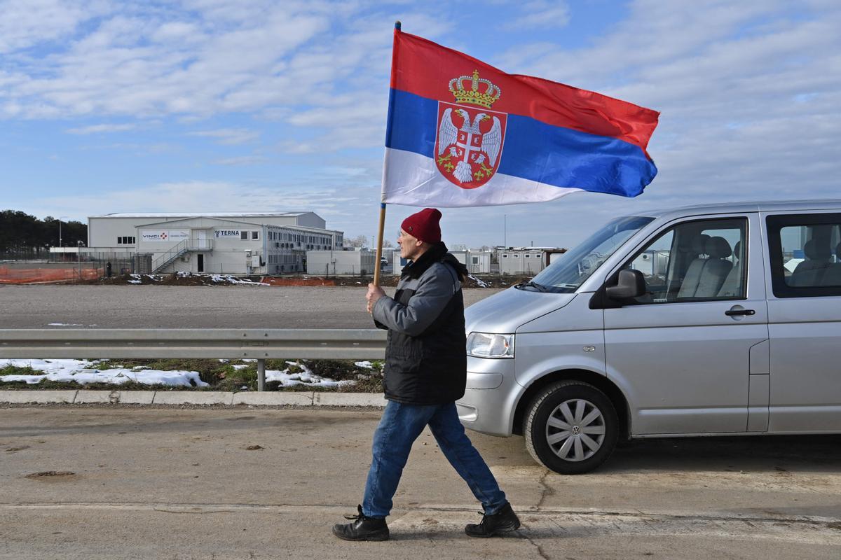 Un seguidor de Djokovic, decepcionado, vuelve a su coche portando una bandera serbia, tras esperar para verlo --sin éxito-- en el aeropuerto de Belgrado.