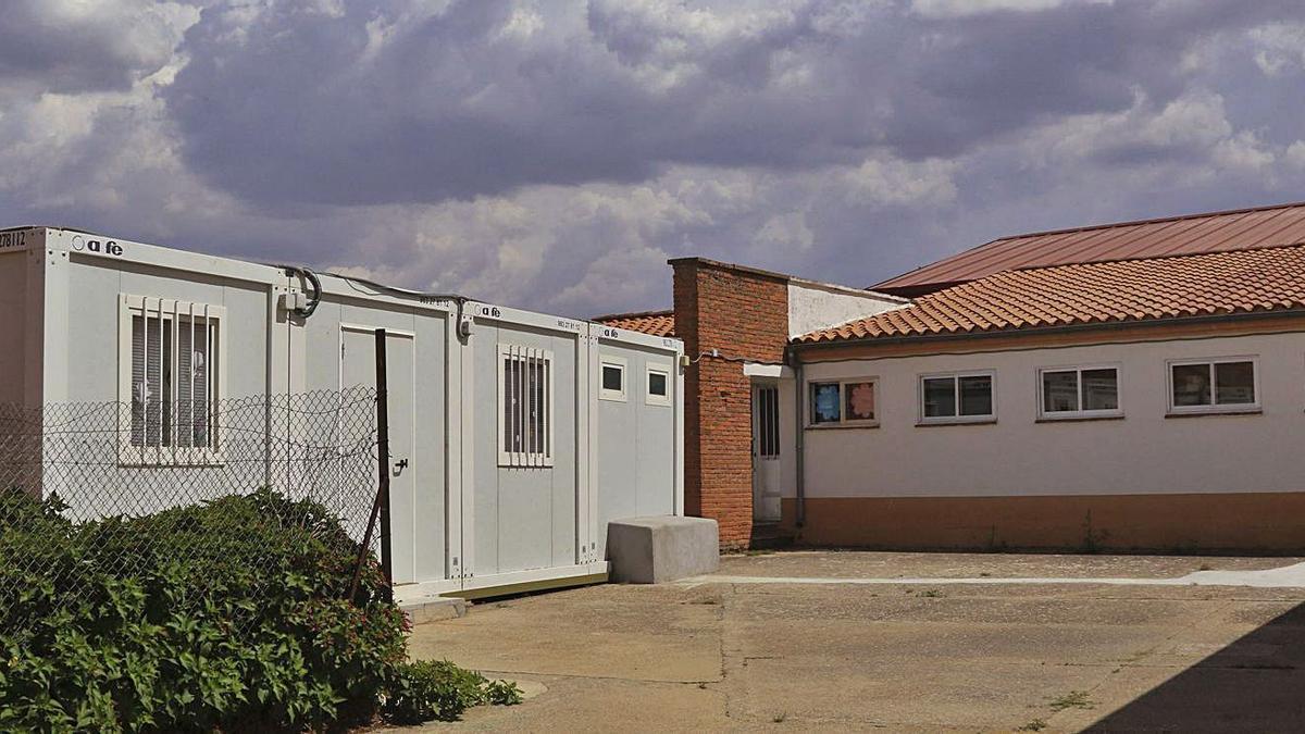 Arriba, aula prefabricada en el patio del colegio de Valcabado. Abajo, plano de la ampliación, señalada con cuadrícula, que ocupará parte del patio (en verde) y del anejo del colegio (en rosa). | Jose Luis Fernández y Junta de Castilla y León