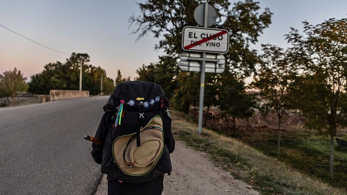 Un peregrino saliendo de la localidad de El Cubo del Vino y a la izquierda dos personas en el albergue de El Cubo. | Nico Rofríguez