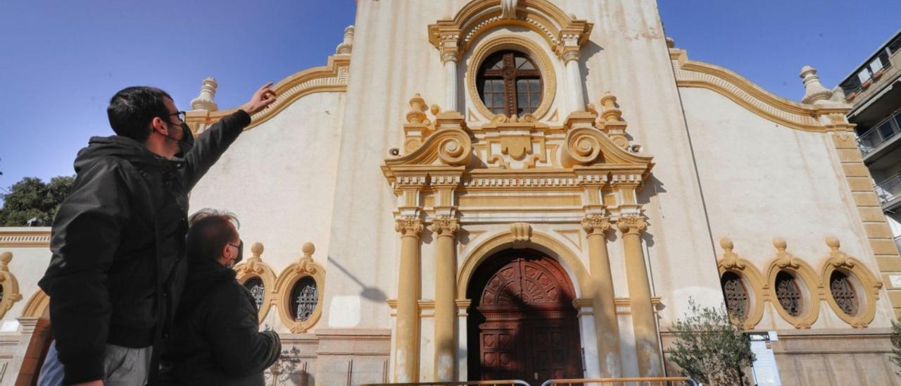 Dos feligreses señalan los daños en la fachada de la iglesia. | DANIEL TORTAJADA