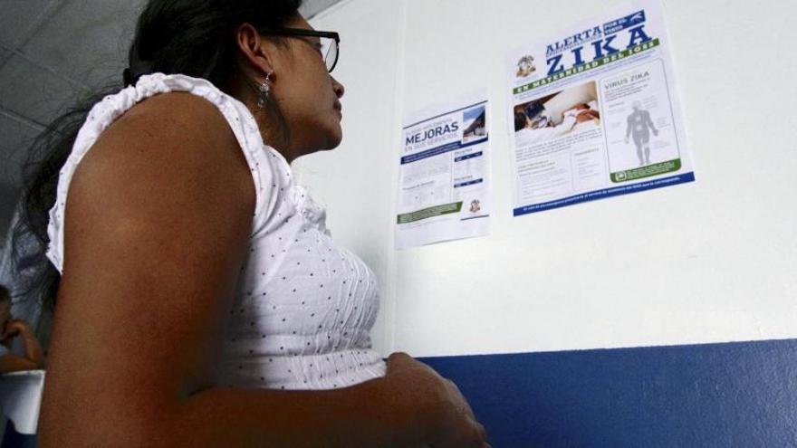 Una dona embarassada consulta un cartell informatiu sobre el Zika