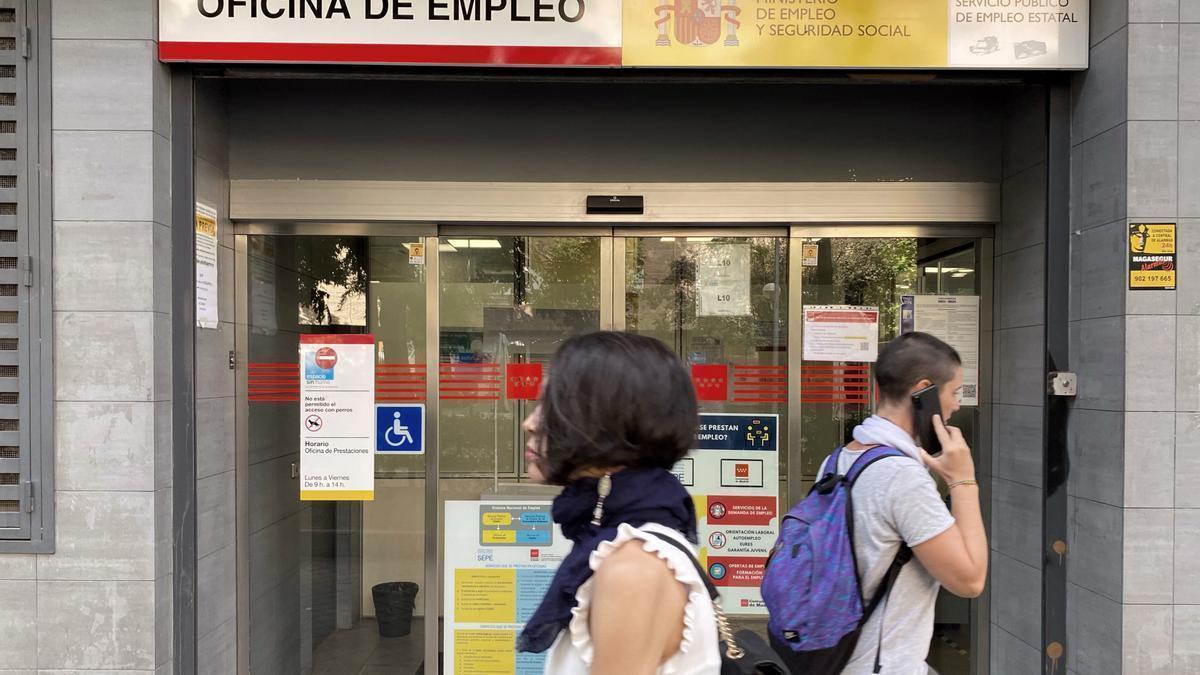 Dos personas pasan ante la entrada de una oficina de empleo.