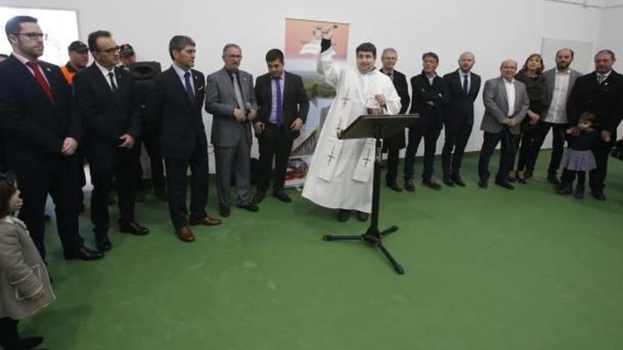 Las autoridades, tras el párroco, en la bendición del gimnasio.