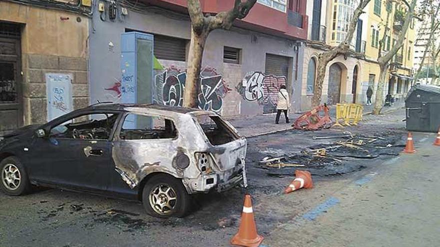 Un coche destrozado junto a los restos de los contenedores consumidos por las llamas, ayer, en la calle Miquel MarquÃ©s.