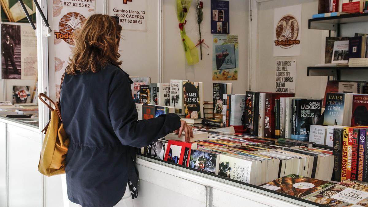 Una lectora ojea una de las casetas de la Feria del Libro de Cáceres.
