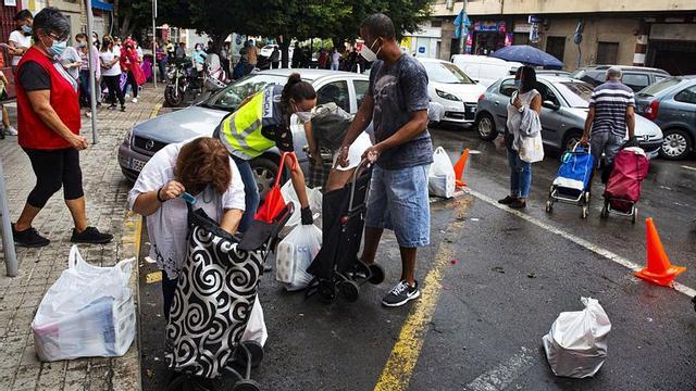 Las colas del hambre, con varias personas que recogen alimentos en la sede de la Despensa Solidaria en Alicante.