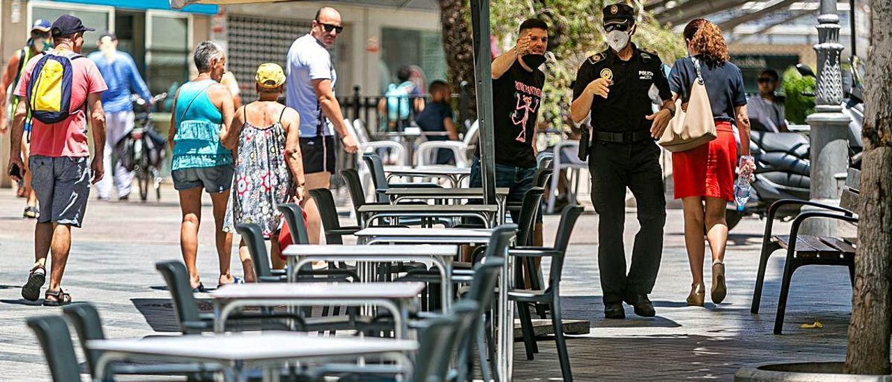 Un policía local indica a los camareros de un bar de la Alameda cómo colocar los veladores.