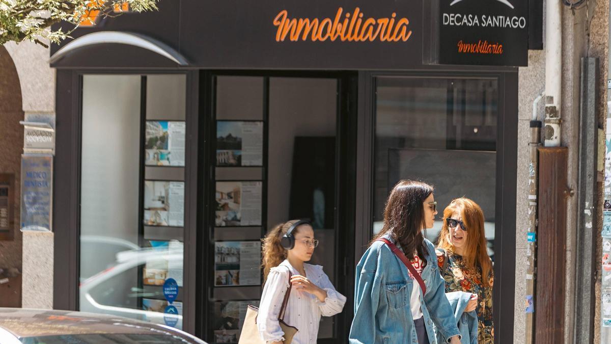 Varias personas caminan por delante del escaparate de una inmobiliaria de Santiago