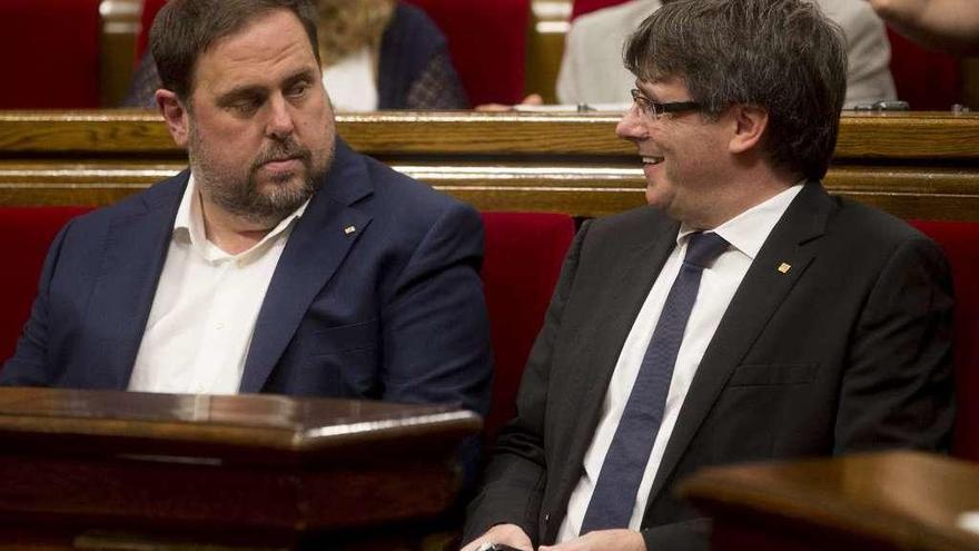 Carles Puigdemont (d.) dialoga con su vicepresidente, Oriol Junqueras, en el Parlament. // Efe