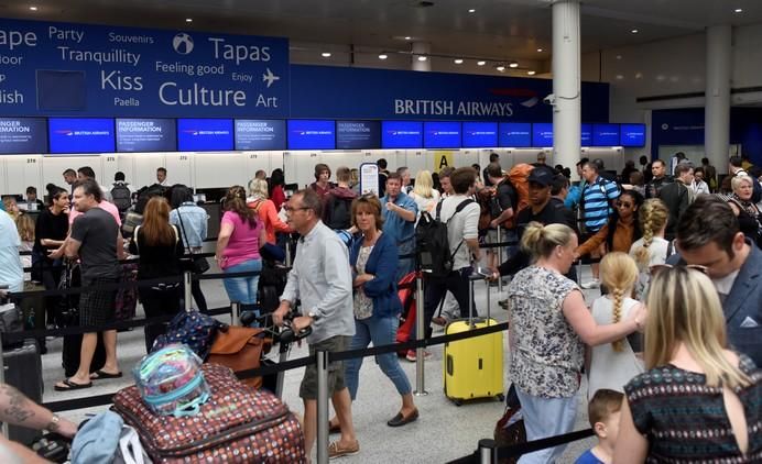 People queue with their luggage for the British ...