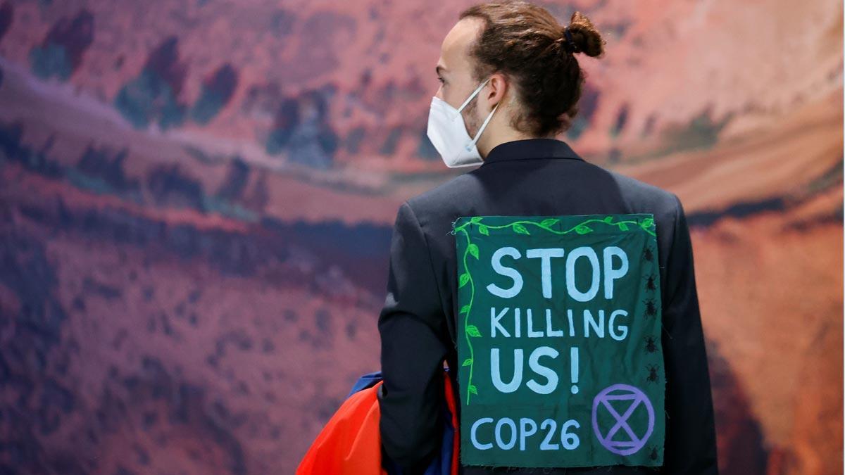 Un asistente a la COP26 viste una chaqueta con el mensaje dejad de matarnos.