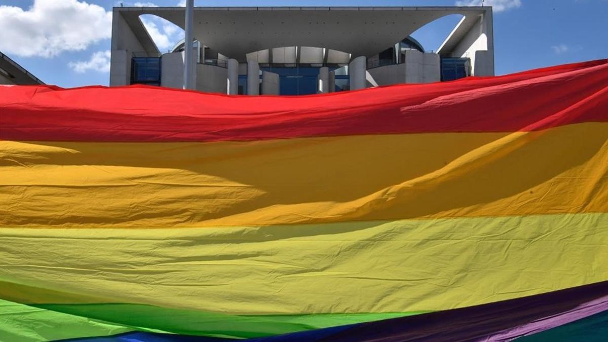 Unos activistas sostienen una bandera arcoiris frente al parlamento en Berlín.