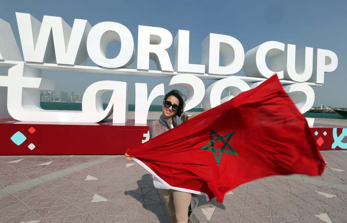 Una fan de Marruecos muestra su bandera junto a unas letras del Mundial de Qatar, en Doha.
