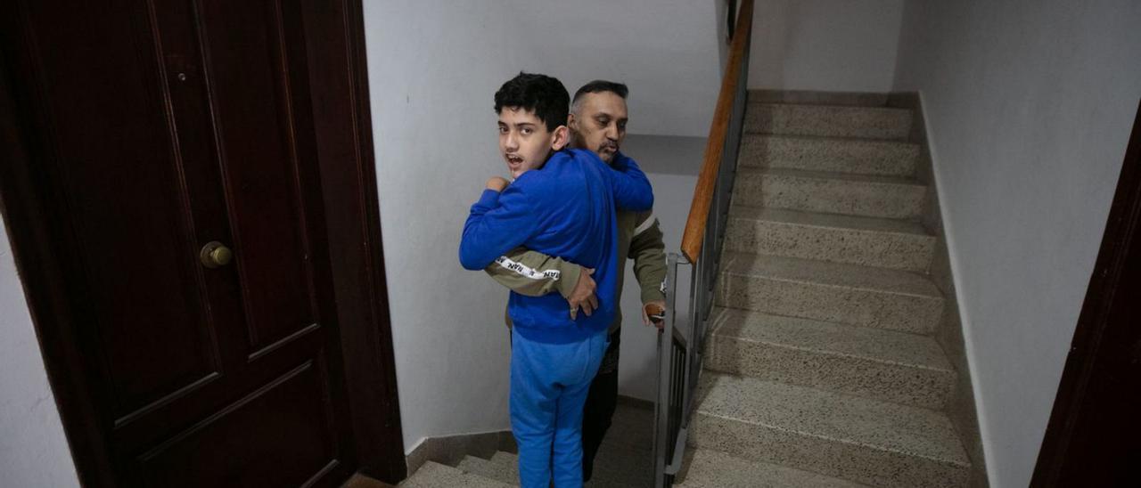 Pese a los intensos dolores que sufre, Arshad Bashir carga a su hijo por la escalera.