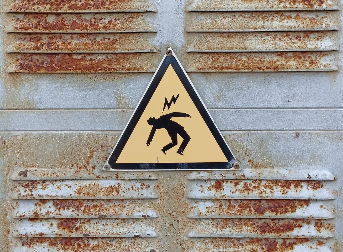 Cartel de peligro en una instalación de la red eléctrica de alta tensión. 