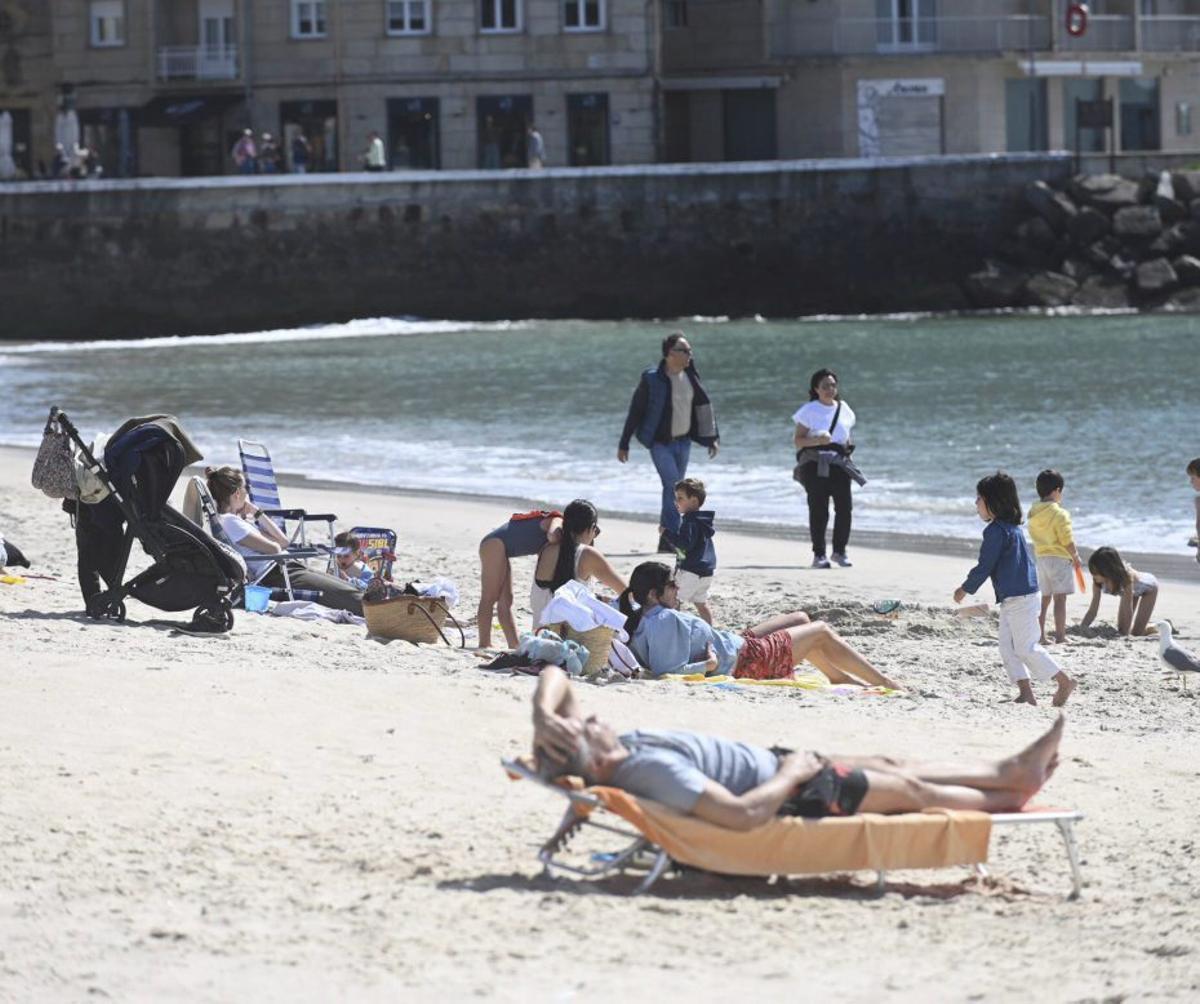 Usuarios de la playa, al sol pero con algo de abrigo. | RAFA VÁZQUEZ
