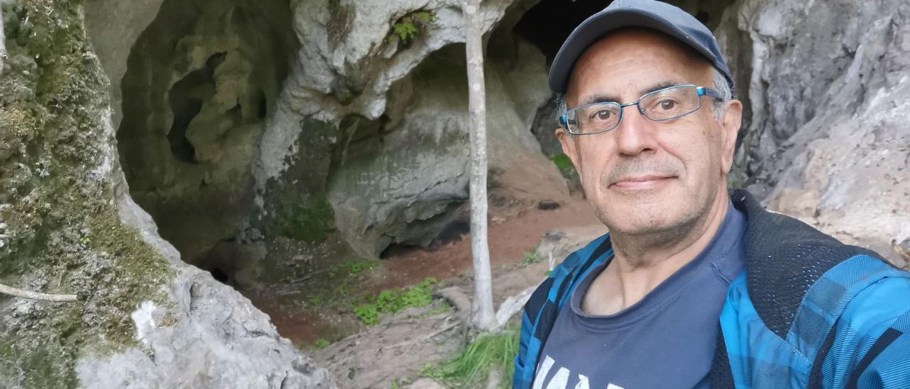 El arqueólogo Antonio Juaneda, ante la entrada a la cueva de Godulfo, en Grado. | Reproducción de Sara Arias
