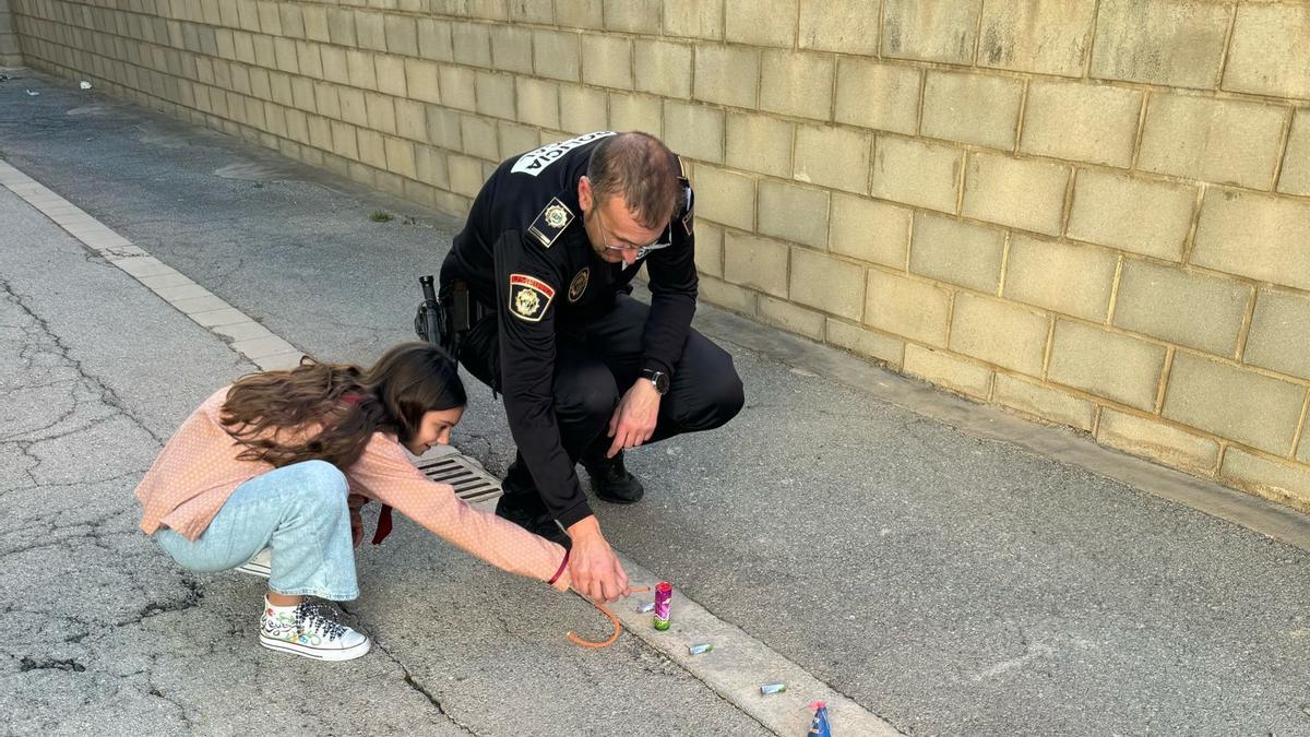 Un agente de policía muestra a una niña cómo disparar petardos de forma segura.