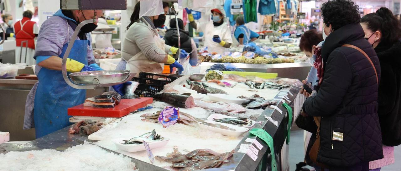 Vigueses comprobando la escasez de algunas especies en los puestos de pescado del mercado de O Calvario, ayer. / ALBA VILLAR