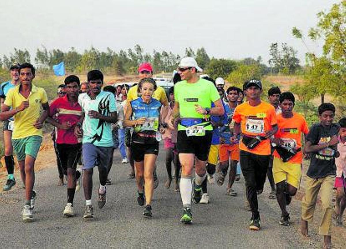 Arriba, un adulto y dos niños con la camiseta de la iniciativa ‘1km 1vida’ alcanzan la línea de meta de la carrera solidaria. | LA PROVINCIA/DLP