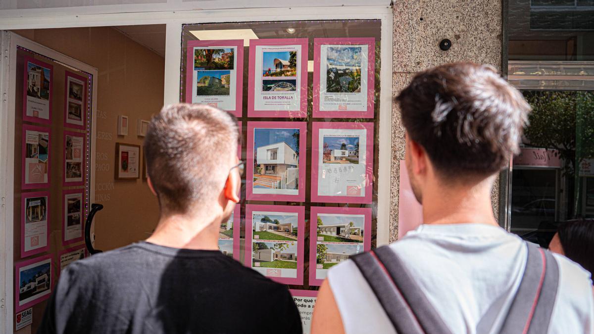 Dos jóvenes ven anuncios de una inmobiliaria.