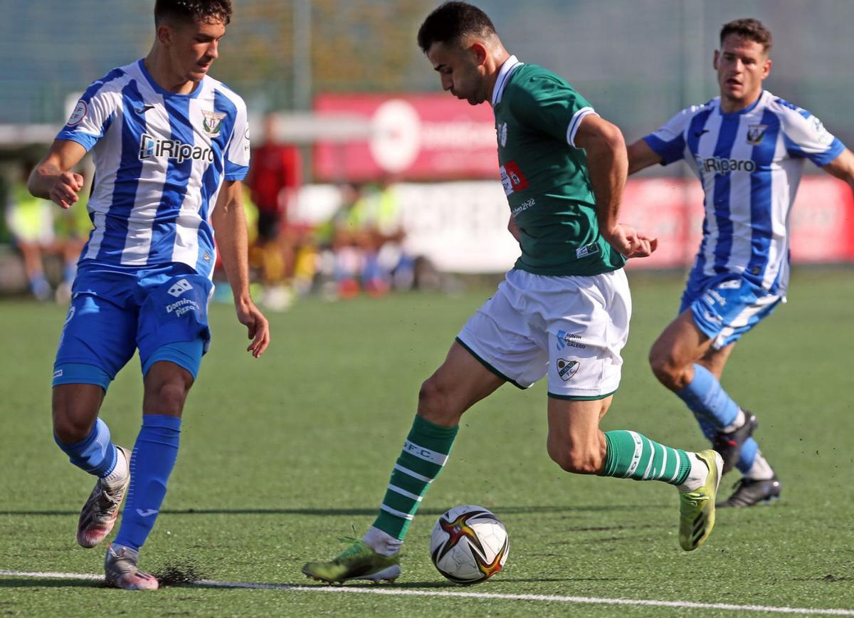 Silva, del Coruxo, conduce el balón ante la presión de un jugador del Leganés B. |  // MARTA G. BREA