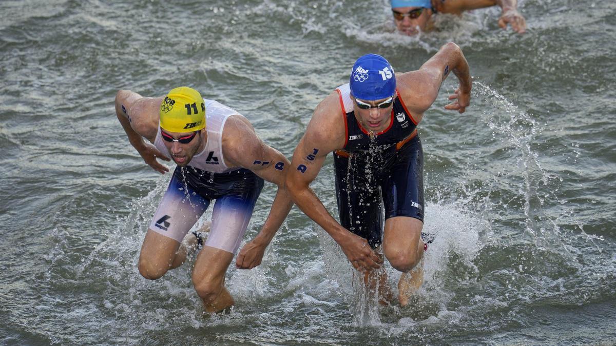 El noruego Vetle Bergsvik Thorn, izq., y el holandés Mitch Kolkman, dcha., saliendo del agua del río Sena tras la prueba de natación del triatlón de relevos mixtos en los Juegos Olímpicos 2024