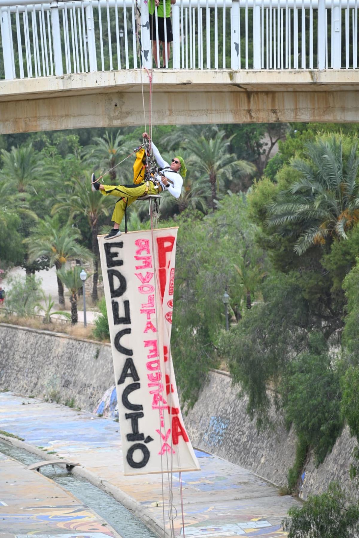 La huelga educativa escala en Elche: un profesor se cuelga de un puente con una pancarta