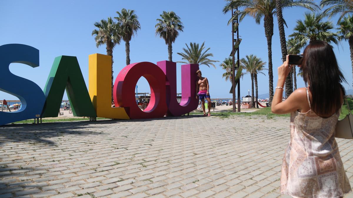 Pla mitjà d&#039;una parella de turistes que es fotografien a les lletres de Salou (Tarragonès). Imatge del 27 de juliol de 2021 (Horitzontal).