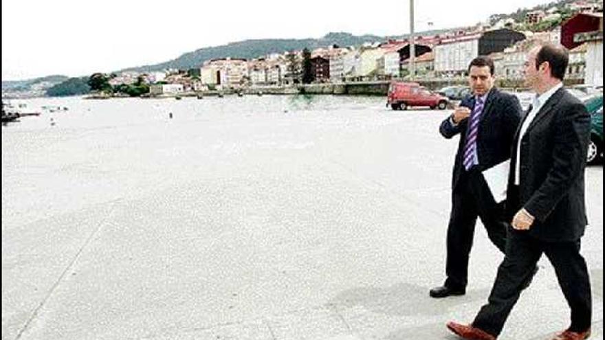 Félix Juncal y Jacinto Parga durante su visita a Bueu y con la playa de Pescadoira al fondo.  / marcos canosa