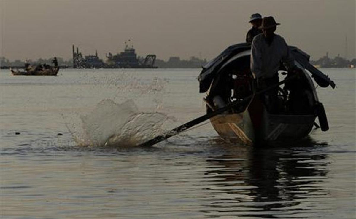 Dos pescadors cambodjans naveguen amb el seu vaixell de fusta pel riu Tonle Sap, a Phom Penh (Cambodja).