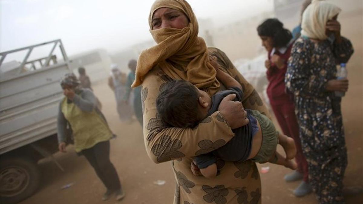 Refugiados kurdos durante una tormenta de arena en la frontera turco-siria cerca de la ciudad de Suruc