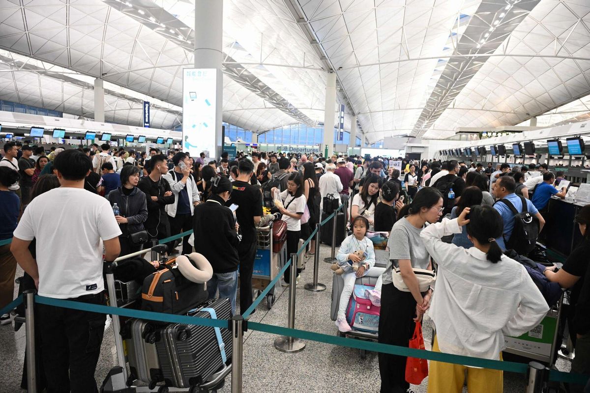 TOPSHOT - A crowd of outbound passengers wait in line to check-in as flights resume at the Hong Kong international airport, while Typhoon Wipha moves away from the city on July 20, 2025. A representative from Hong Kongs Airport Authority earlier said that around 500 flights have been cancelled due to the weather, while around 400 flights were scheduled to take off or land later in the day. (Photo by Peter PARKS / AFP)