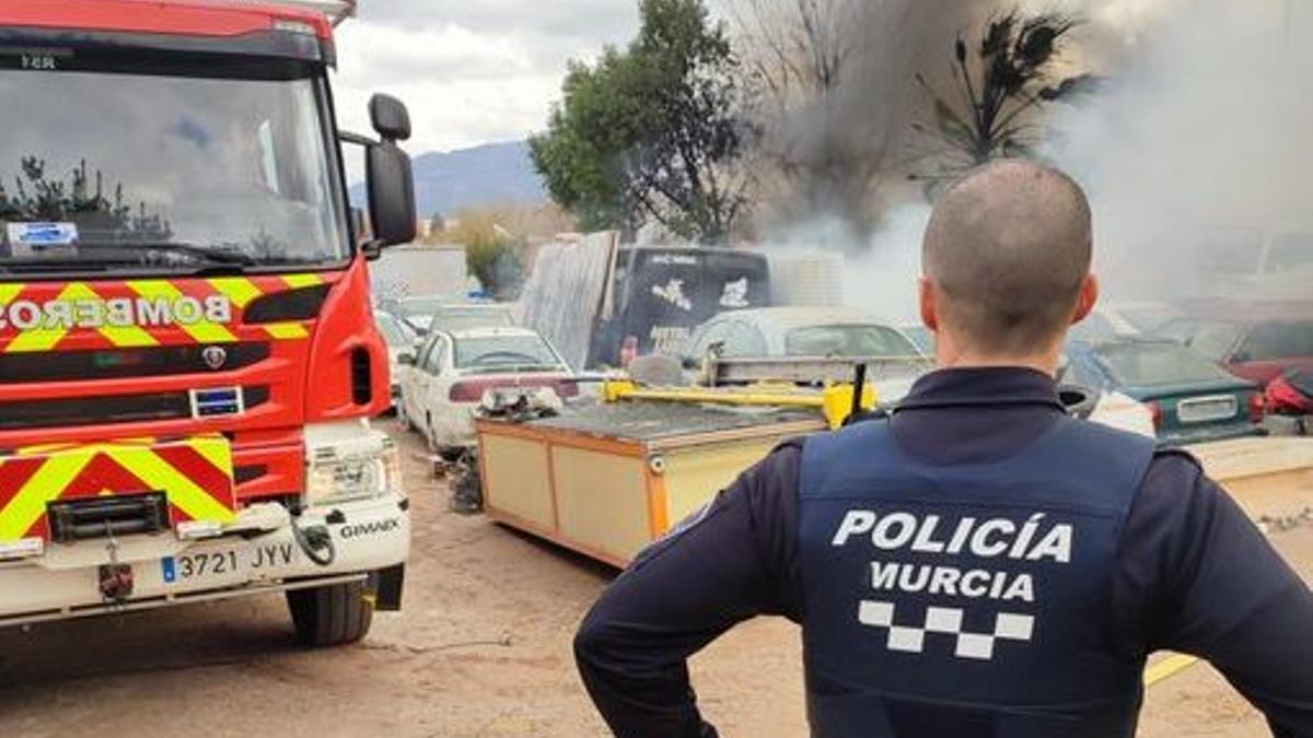 Un agente de la Policía Local, junto a la columna de humo y un camión de Bomberos.