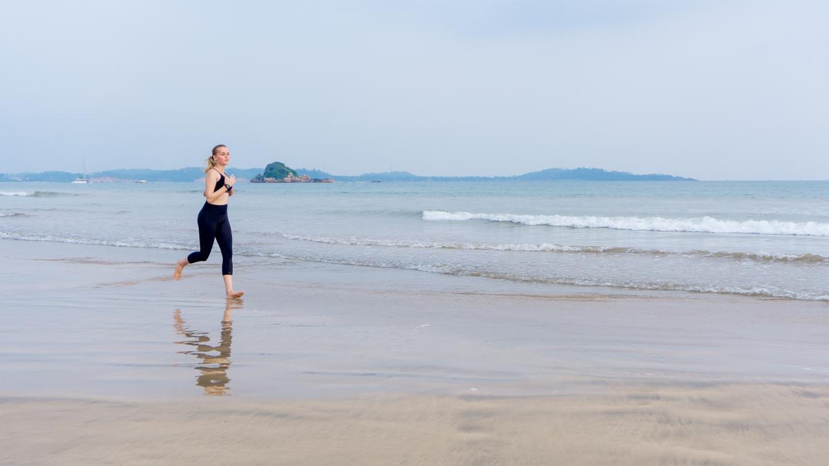 Una chica corriendo descalza por la playa