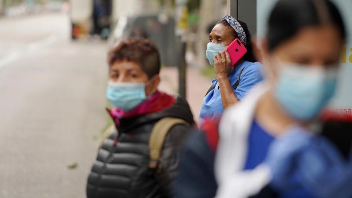 Varias personas hacen cola en la parada de un autobús, esta semana en Madrid.