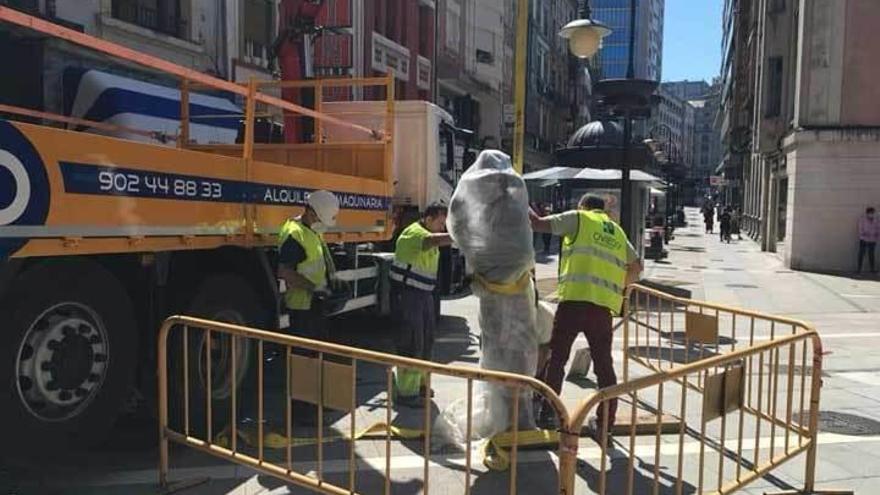 Los operarios retiran la estatua de la calle Palacio Valdés.