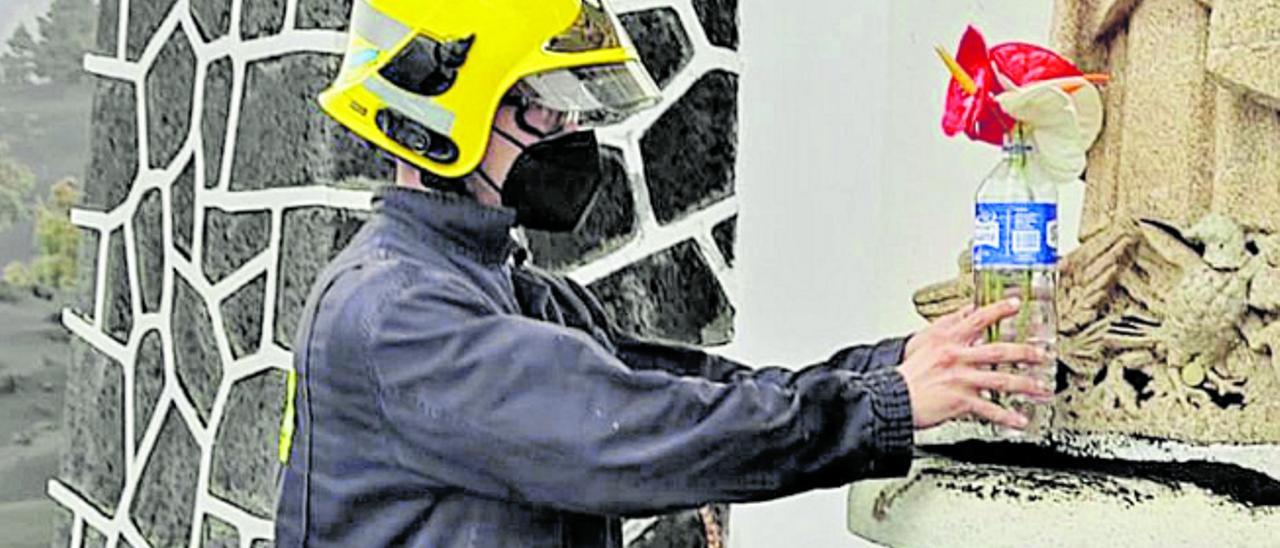 Un bombero deposita la flor a los pies del monumento religioso.