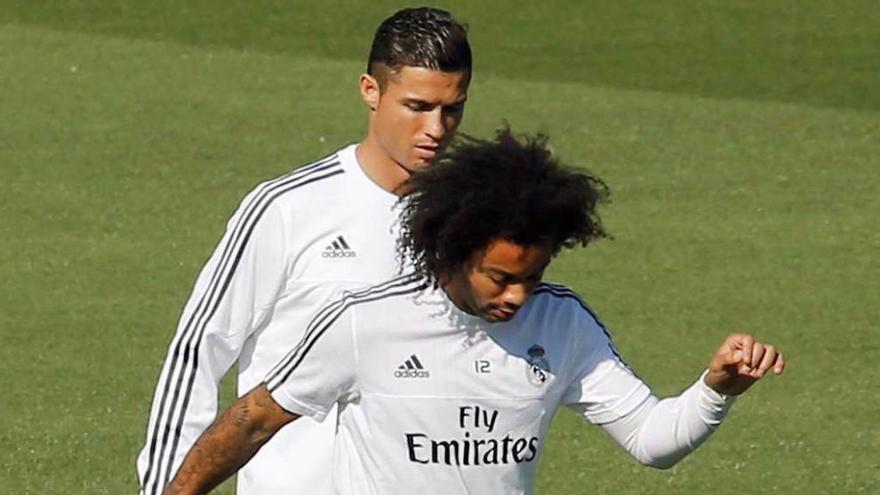 Marcelo toca el balón por delante de Cristiano Ronaldo.