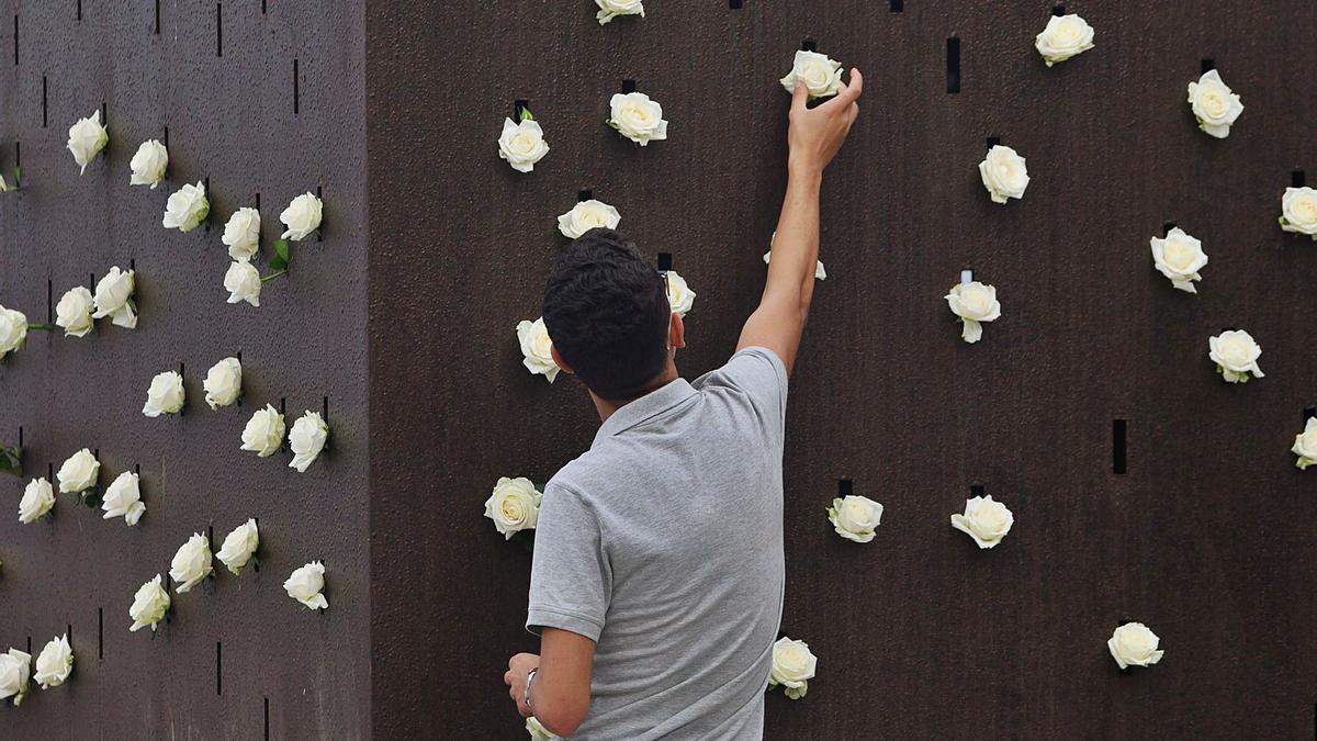 Un chico coloca una rosa blanca en el monumento ‘Luces en el vacío’, durante el homenaje a las víctimas de 2019.