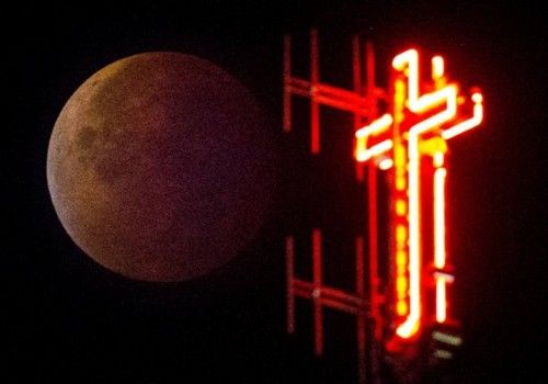 The cross of the Koekelberg Basilica is seen while the moon turns orange during a total "supermoon" lunar eclipse in Brussels