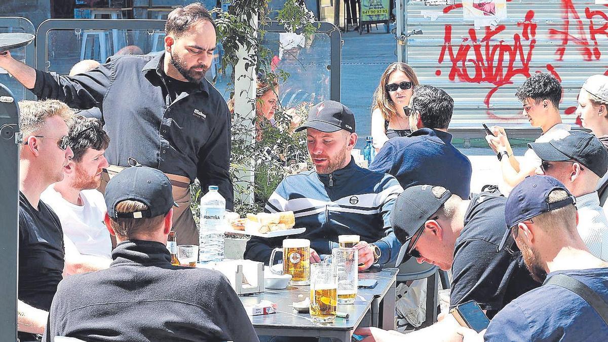 Un camarero atiende una mesa en una terraza de la ciudad de Vigo