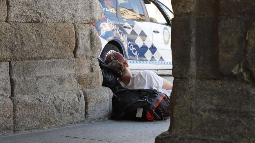 Una peregrina durmiendo en el suelo junto a un coche patrulla