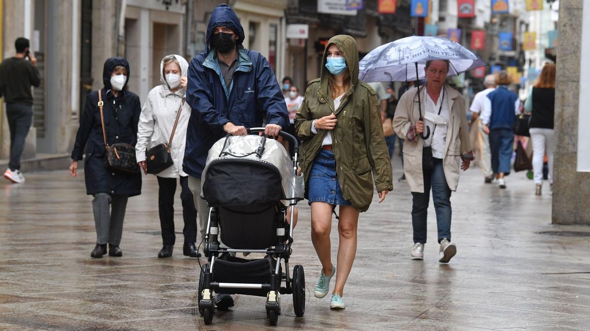 Gente pasea con paraguas en la calle Real de A Coruña.